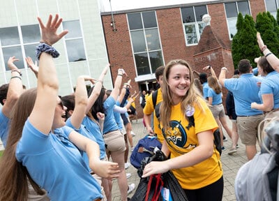 An admitted student enters campus for orientation among a crowd of cheering students