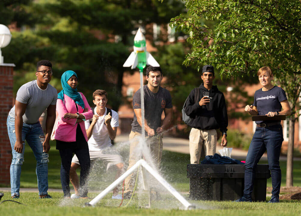 Students and a professor launch a bottle rocket they made into the air