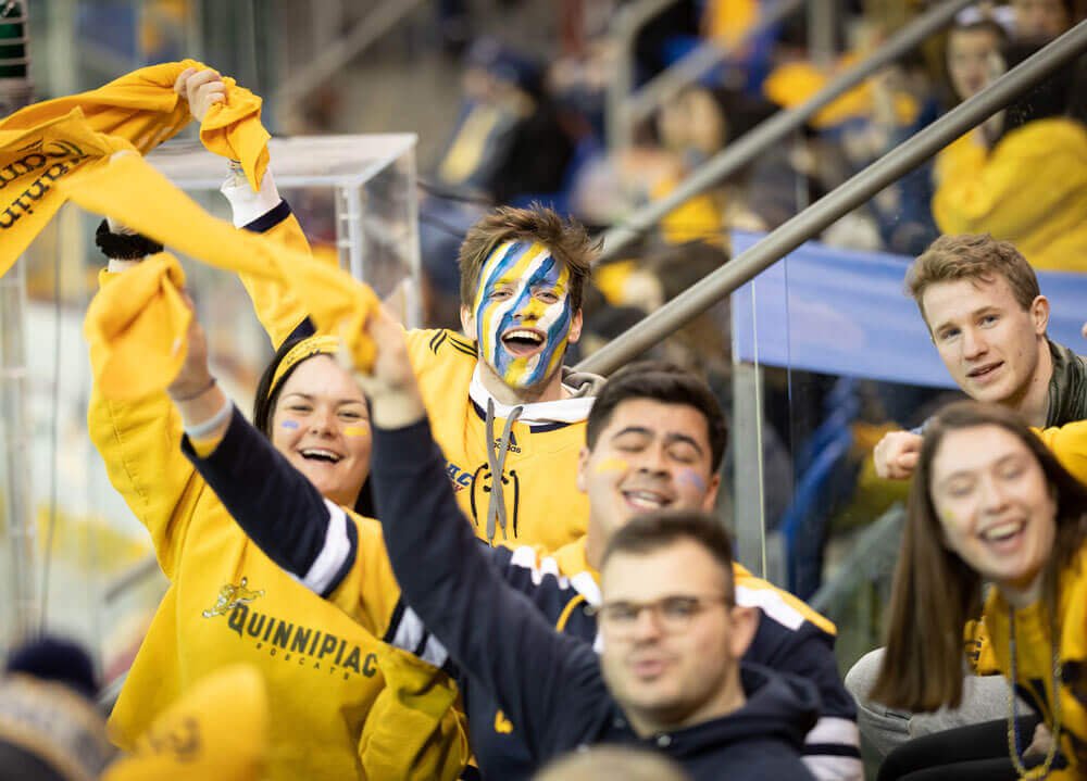Students in bobcat gold cheer at a hockey game